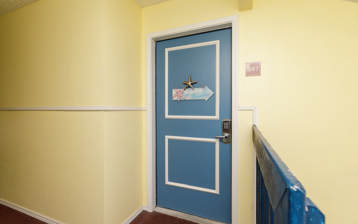 Your welcoming retreat awaits behind this cheerful blue door, where warm yellow hallways create an instantly inviting atmosphere for your stay.