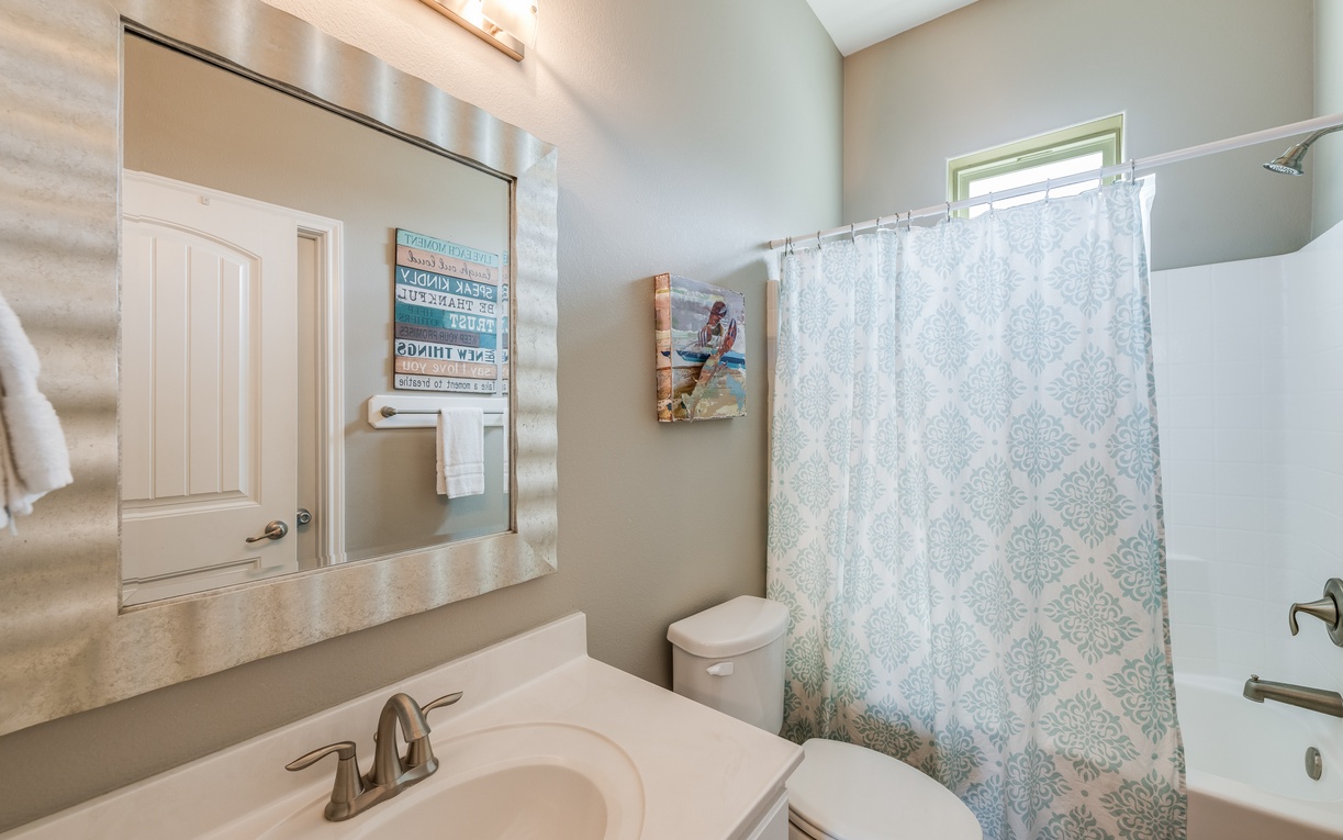 Step into your private bathroom featuring a spacious vanity, modern fixtures, and a relaxing tub-shower combo with cheerful coastal decor.