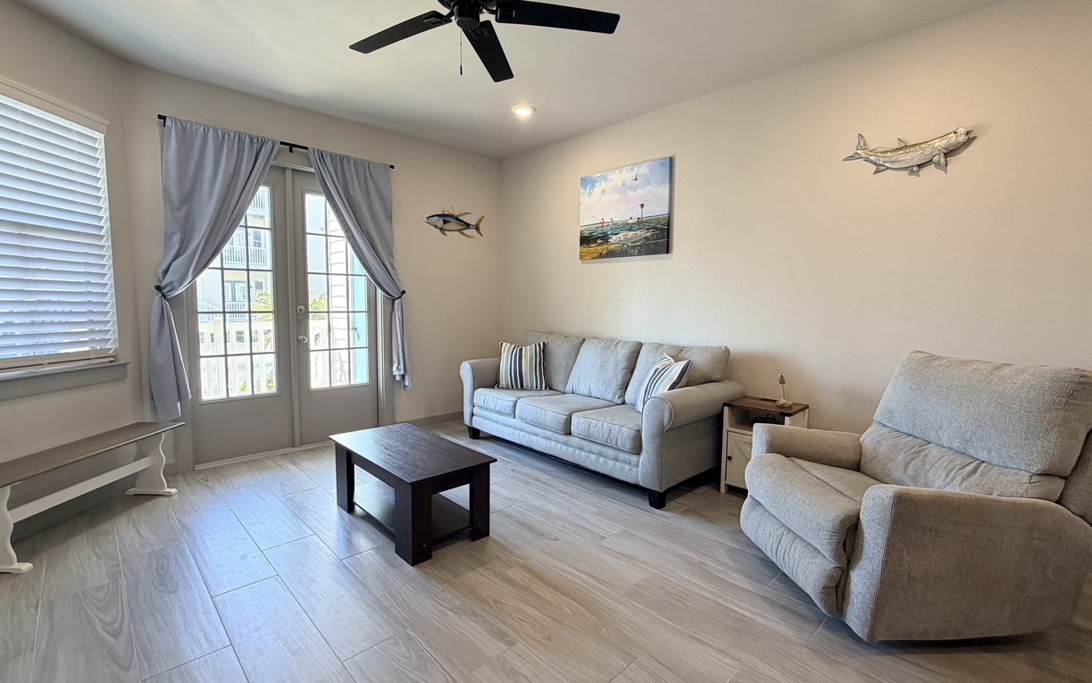 Relax in your comfortable living space with plush seating, coastal decor, and French doors leading to your private balcony.