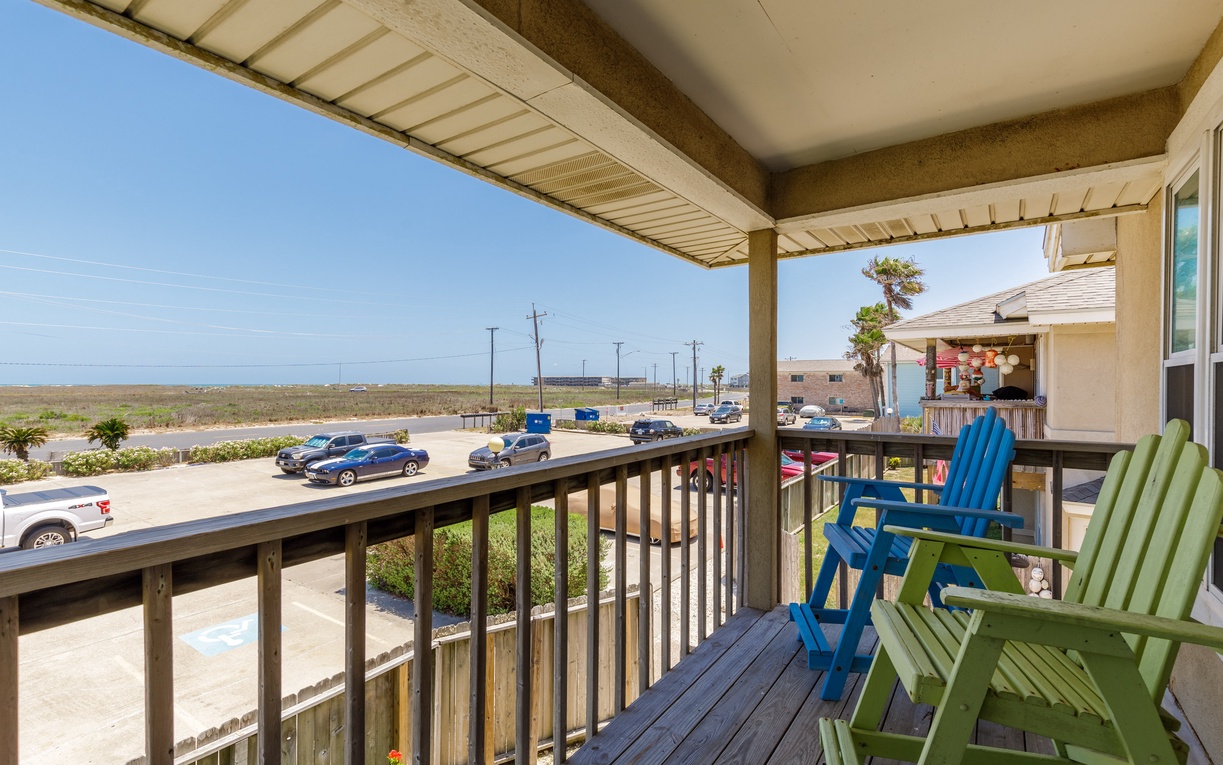 Relax in colorful beach chairs on your private balcony, watching coastal life unfold below while enjoying refreshing ocean breezes.