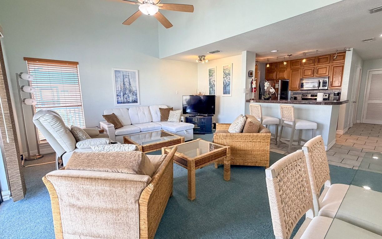 Relax in your spacious open-concept living area with plush seating, modern kitchen, and coastal decor creating the perfect home base.