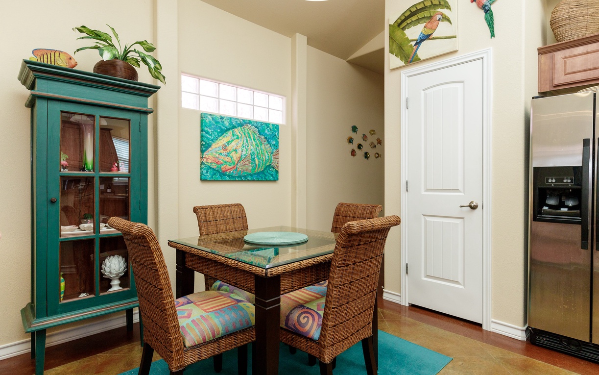 Your tropical-themed dining nook welcomes you with wicker chairs and vibrant artwork, perfect for morning coffee or intimate meals together.