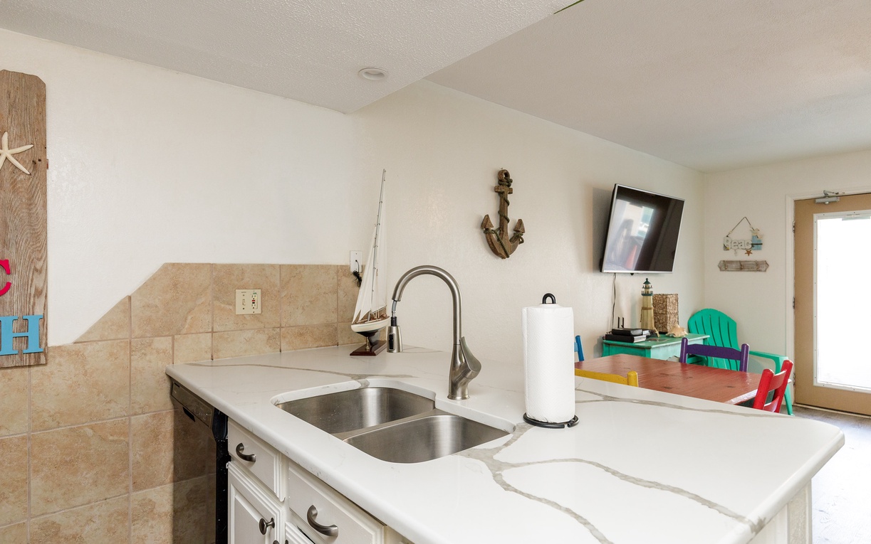 Your nautical-themed kitchen features elegant marble countertops, stainless steel sink, and charming coastal décor that makes meal prep feel like a seaside retreat.