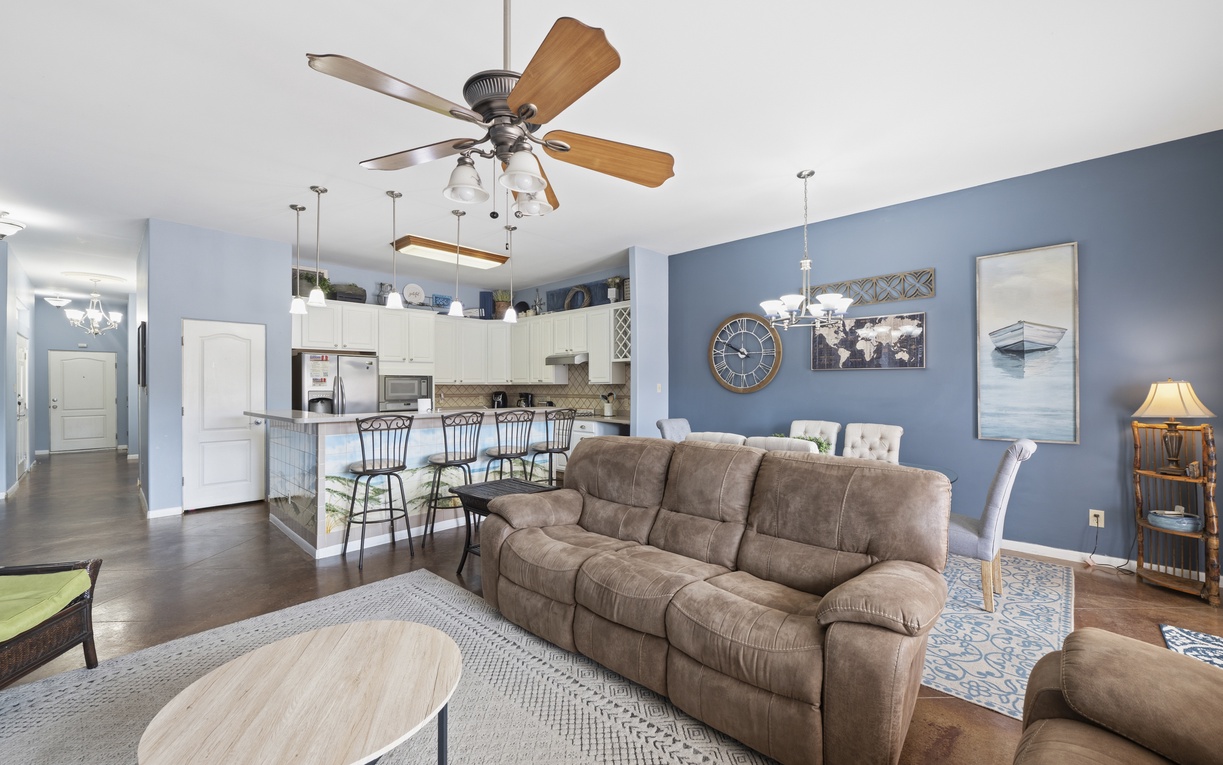 Picture yourself in this inviting open-plan retreat where coastal blues wrap around you. Sink into the plush sofa, feel the cool air from the ceiling fan, and savor meals at your breakfast bar overlooking everything.