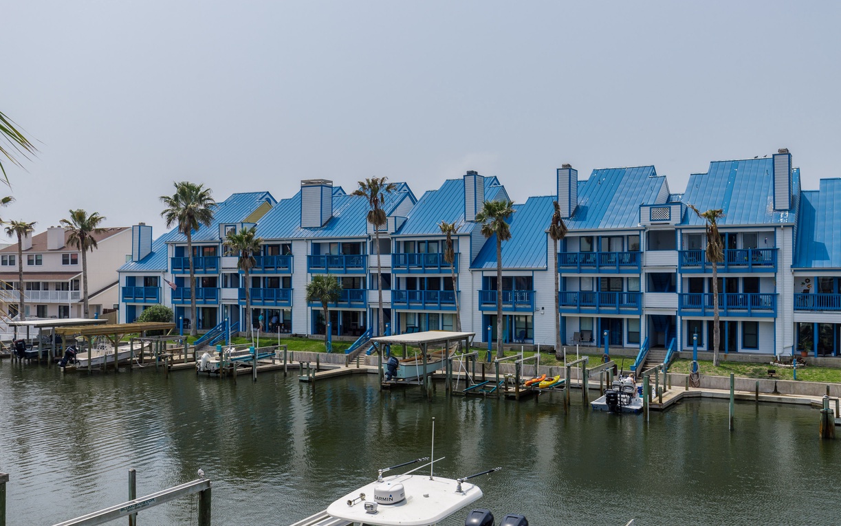 Waterfront condominiums with distinctive blue roofing and private boat docks along the marina.