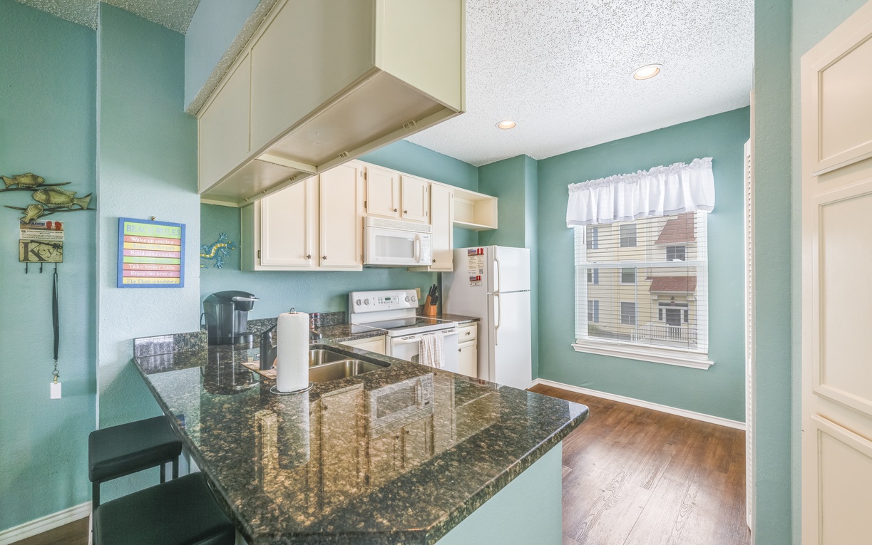 Bright, fully equipped kitchen with granite countertops, modern appliances, and an open layout that makes preparing meals easy and enjoyable.