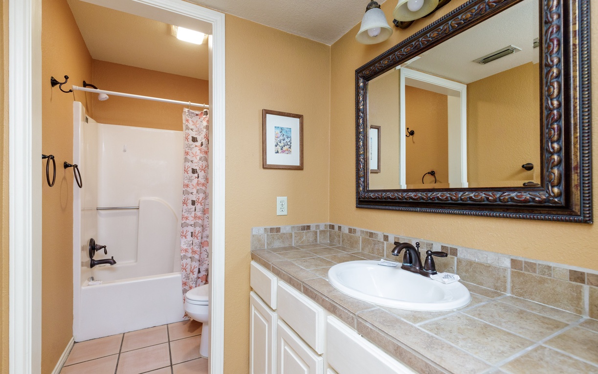 Refresh in your elegant bathroom with tiled countertops, ornate mirror, and separate tub-shower combo for ultimate relaxation.