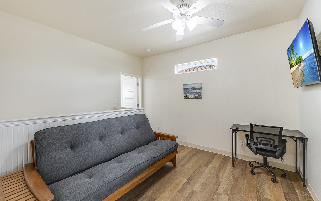 Your dedicated workspace features a comfortable futon and modern desk, perfect for productive moments with the ceiling fan keeping you cool.