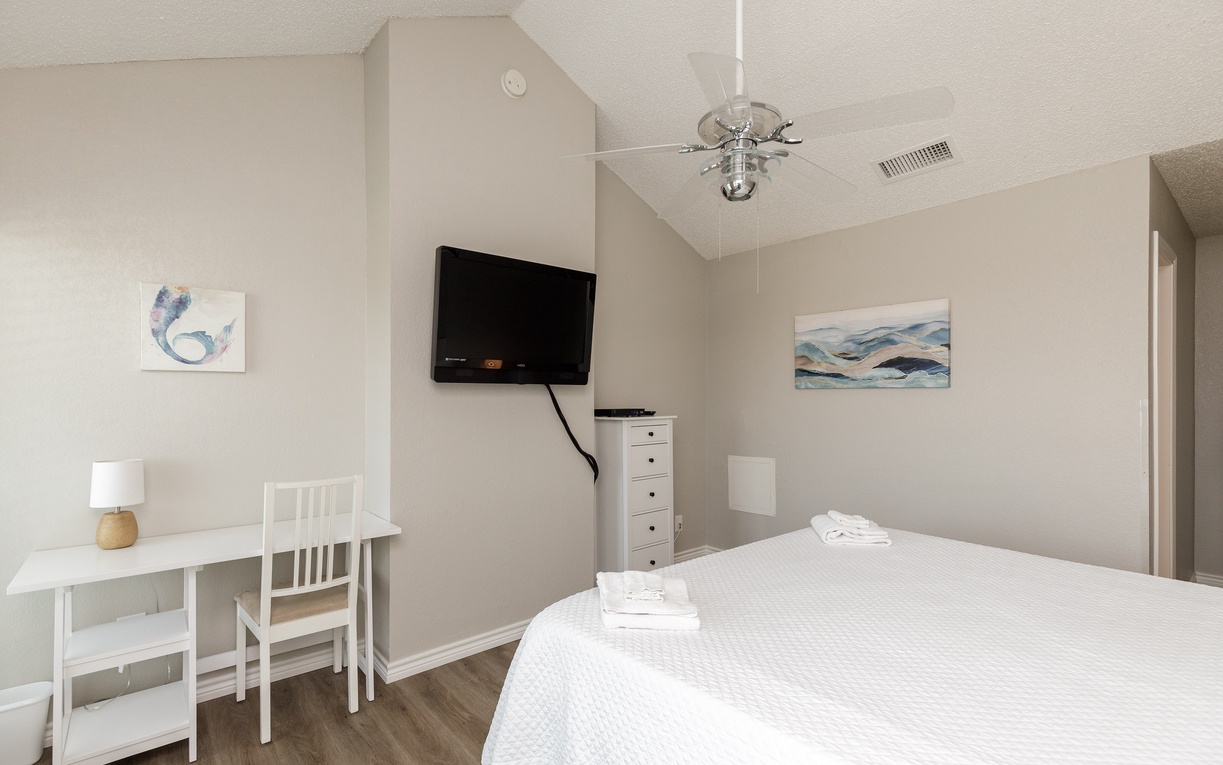 Unwind in your peaceful bedroom with crisp linens, modern amenities, and coastal artwork creating a serene retreat for restful nights.