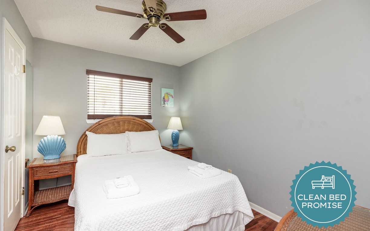 Drift off peacefully in your cozy coastal bedroom with crisp linens, warm wicker touches, and gentle ceiling fan breeze.