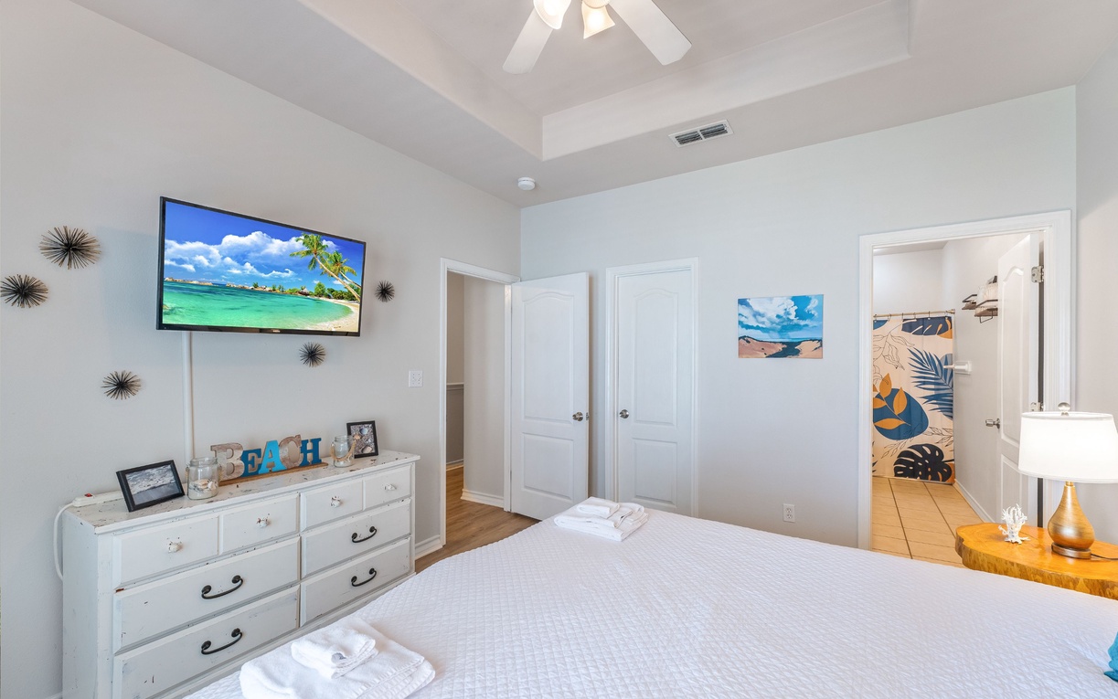 Relax in your bright bedroom featuring coastal decor, wall-mounted TV, and ensuite bathroom access for ultimate convenience.