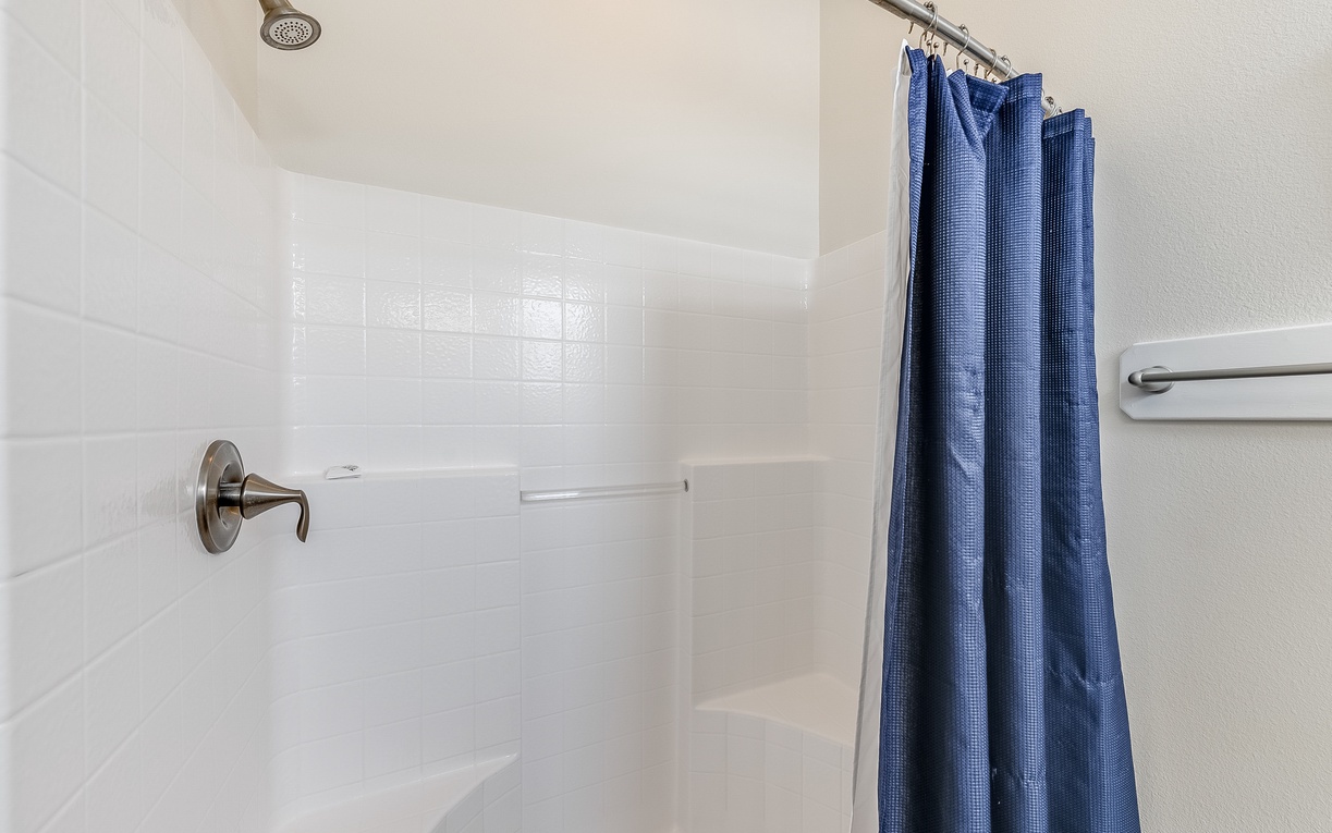 Step into your private shower with crisp blue curtains and modern fixtures for refreshing mornings.