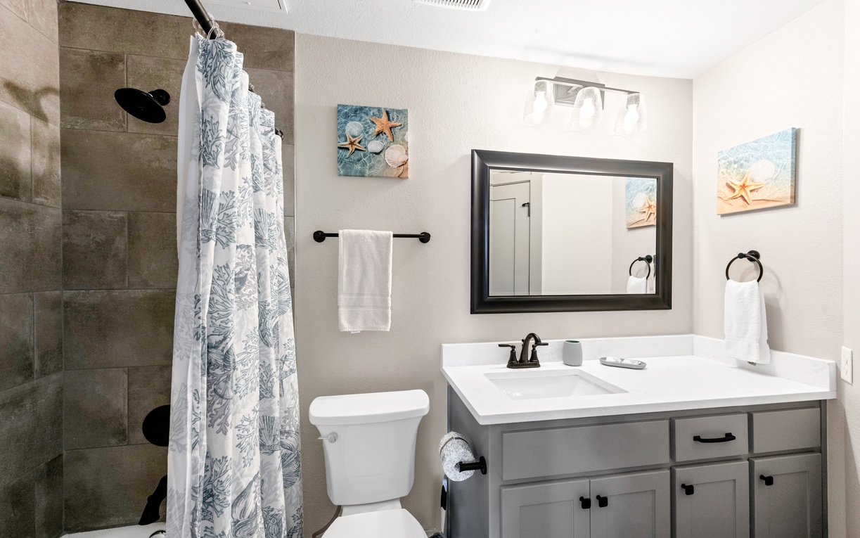 Refresh in your beautifully updated bathroom with coastal charm, featuring a spacious tiled shower and elegant vanity.
