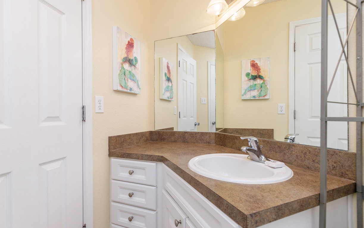 Refresh in your bright bathroom featuring granite counters, white cabinetry, and cheerful artwork that makes your morning routine a delight.