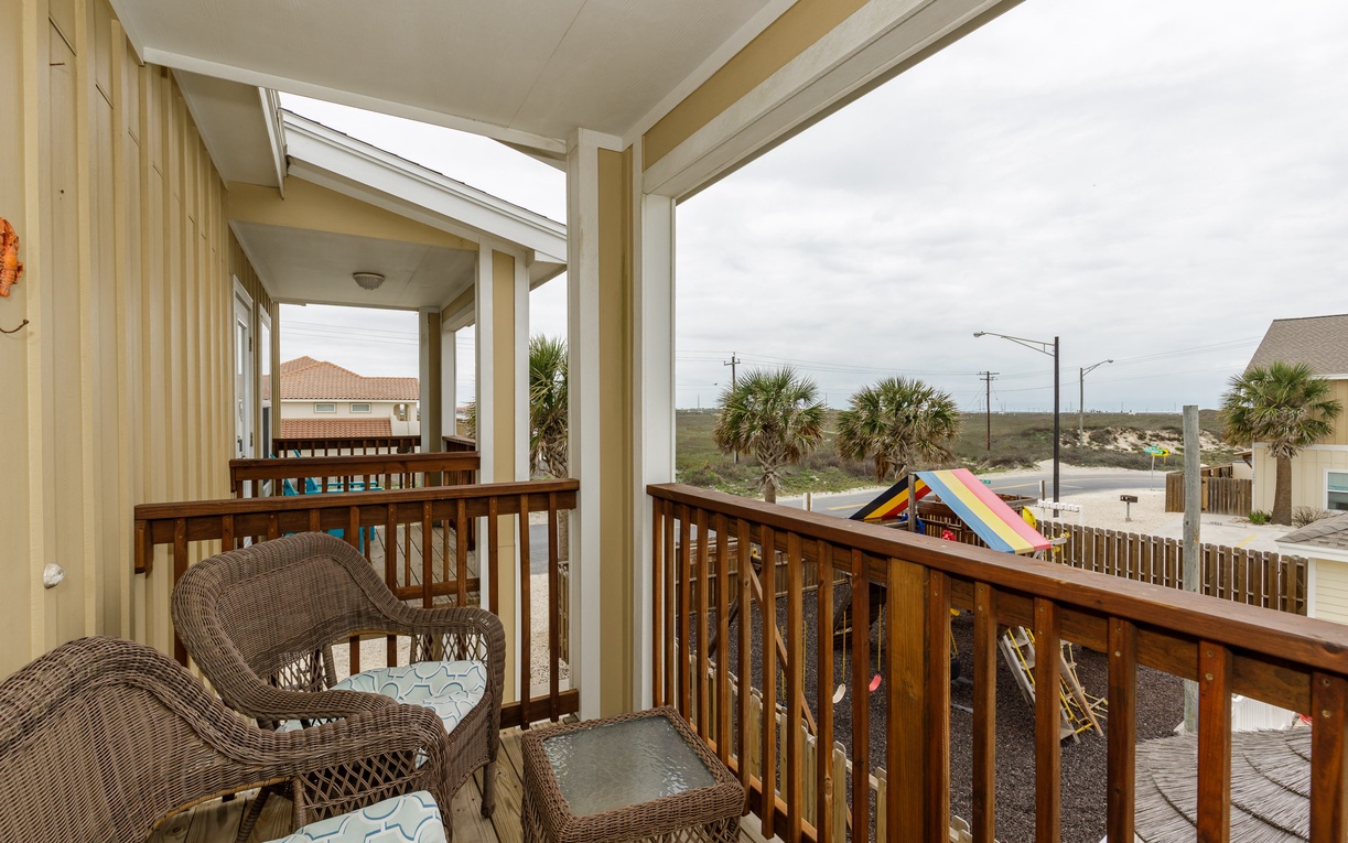 Relax on your covered balcony with comfortable wicker seating while enjoying peaceful views of palm trees and the coastal neighborhood.