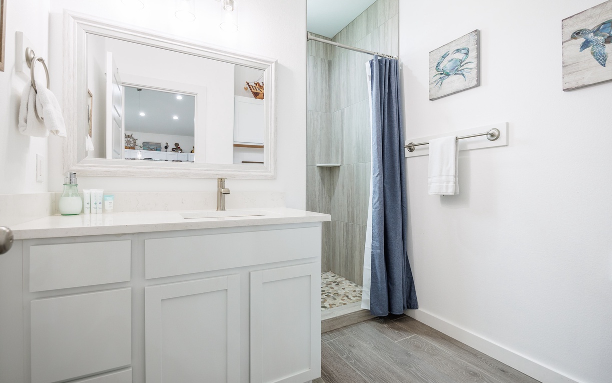 Refresh in your beautifully appointed bathroom with coastal charm, featuring a spacious vanity and tiled shower.