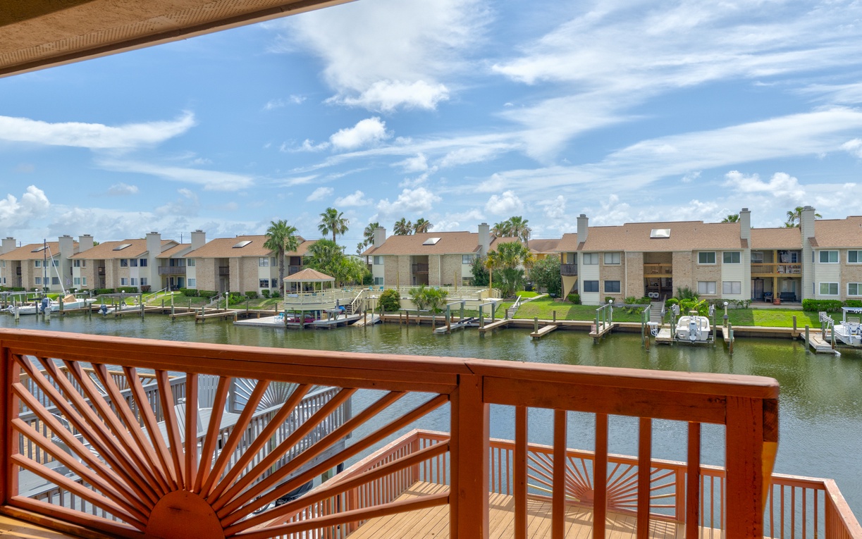A serene waterfront community features private boat docks, lush green lawns, and swaying palms beneath blue skies—your gateway to coastal living.