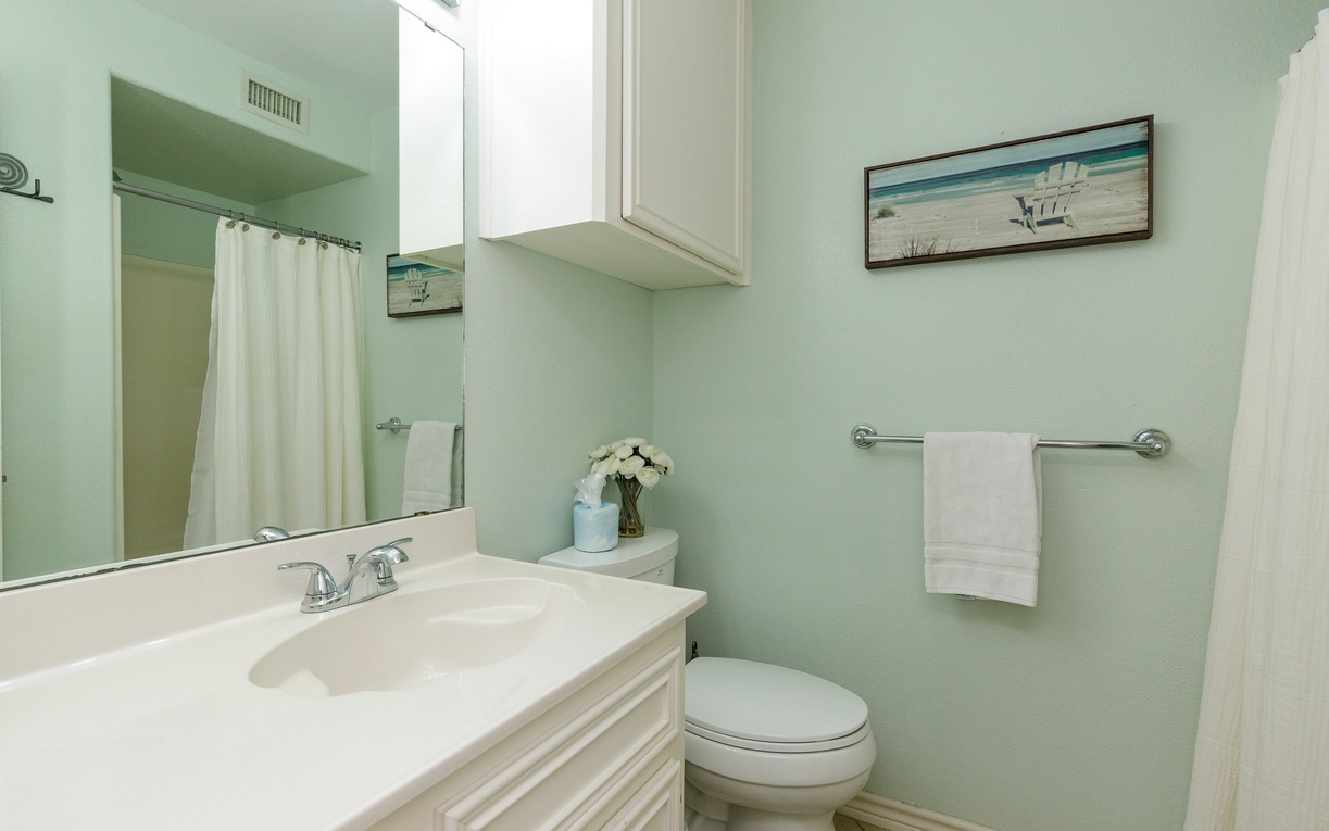 Refresh in your serene coastal bathroom with soothing mint walls, crisp white linens, and beachy artwork that instantly transports you to vacation mode.