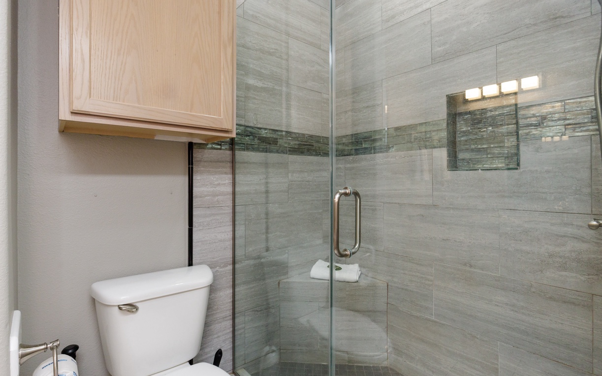 Step into your spa-like bathroom featuring a spacious walk-in shower with elegant stone-look tiles and modern glass enclosure.