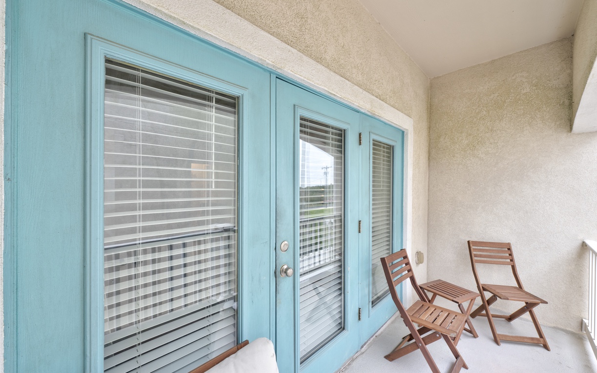 Your private balcony awaits with cozy wooden chairs and charming turquoise French doors—perfect for morning coffee or evening relaxation.