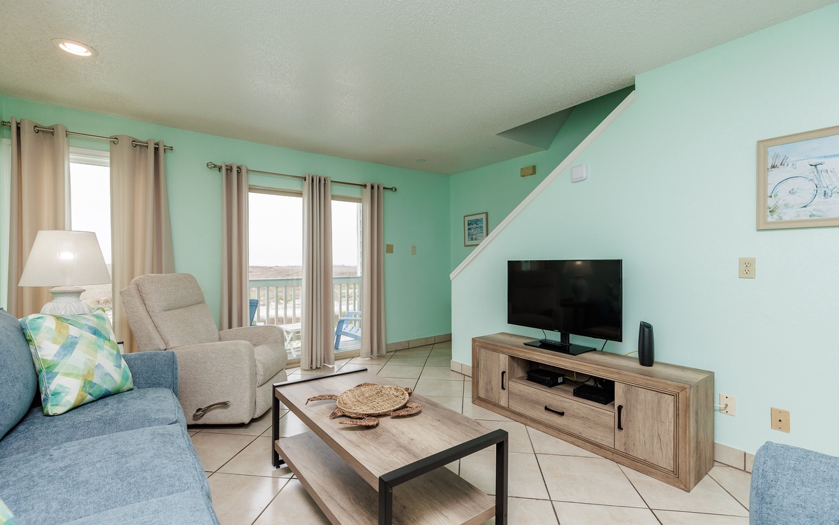 Settle into your coastal-themed living room with comfy seating and entertainment center, perfect for unwinding after beach adventures.