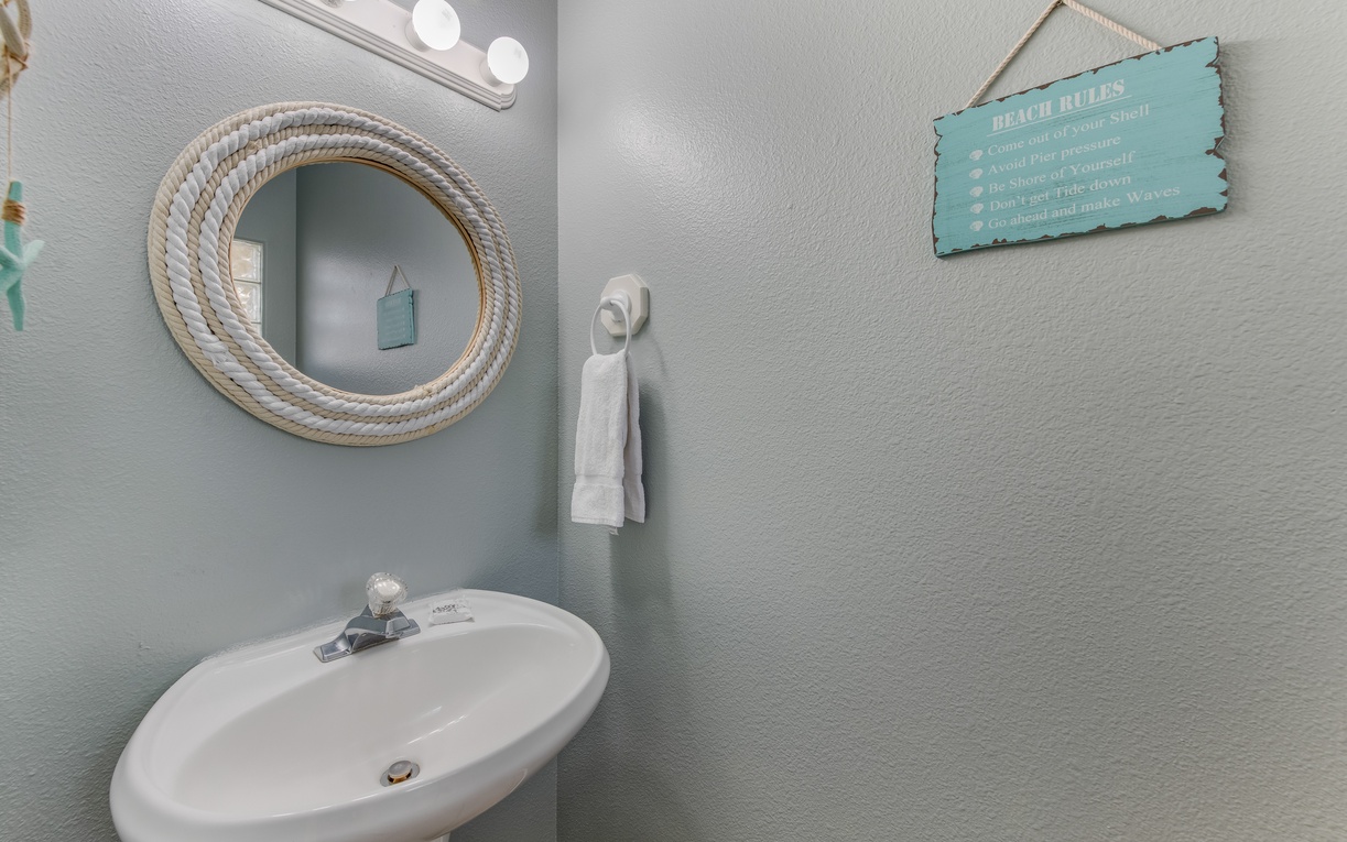 Refresh in your charming coastal-themed bathroom with rope-framed mirror and beachy decor that creates a relaxing seaside atmosphere.