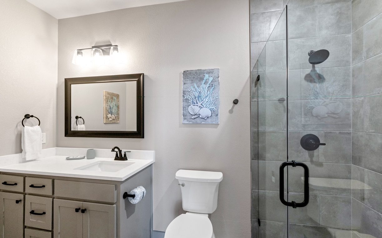 Refresh in your modern bathroom with sleek glass shower and coastal artwork adding serene touches to your daily routine.