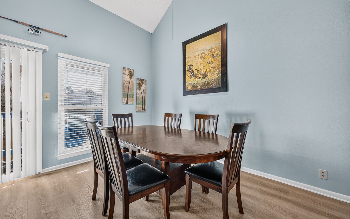 Enjoy meals together in this charming dining area featuring a rich wooden table, comfortable seating for six, and coastal blue walls that create a warm and welcoming atmosphere.