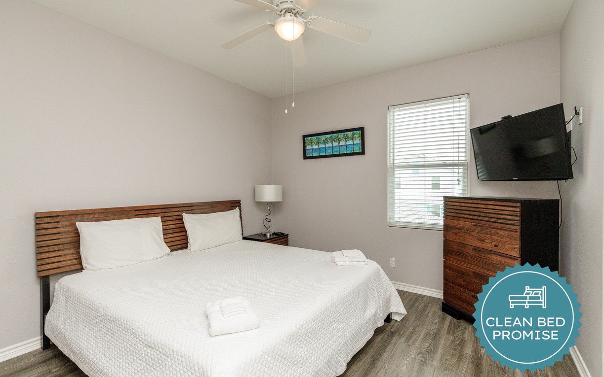 Unwind in your peaceful bedroom featuring a plush bed, modern amenities, and gentle ceiling fan for perfect comfort.