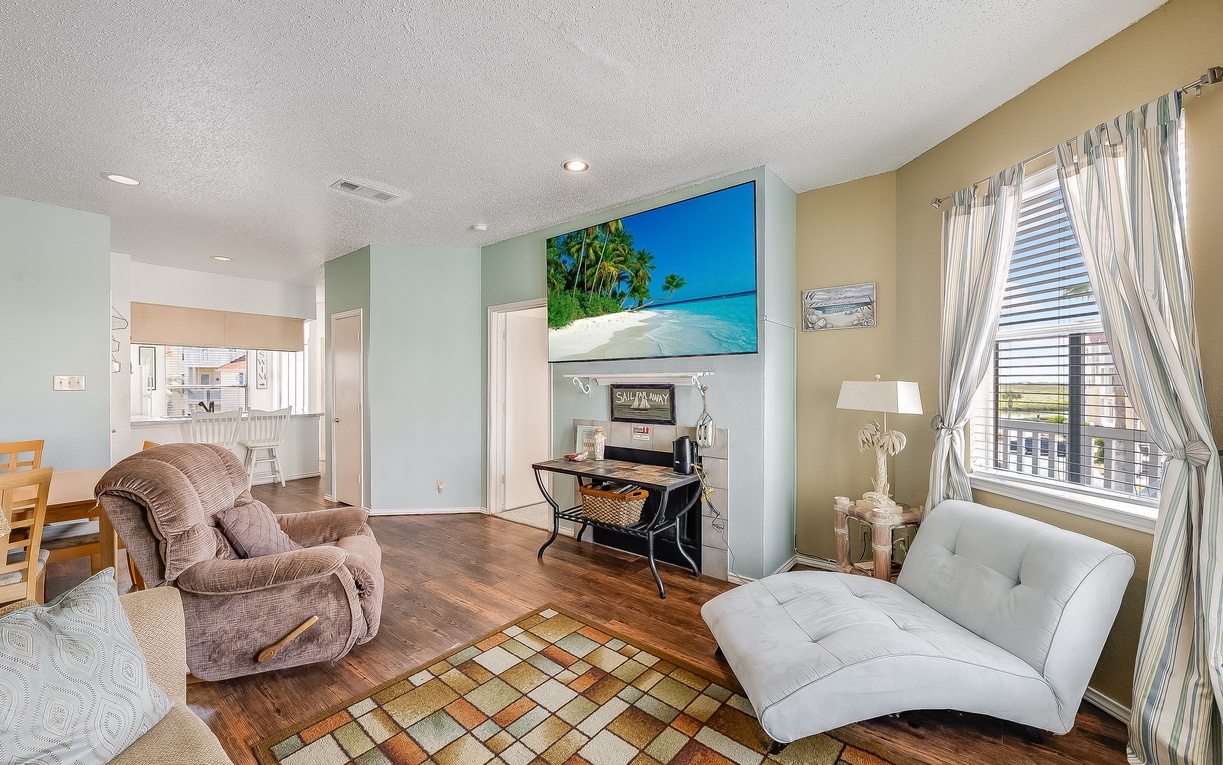 Relax in your bright living space with cozy seating, tropical artwork, and a peaceful workspace corner.