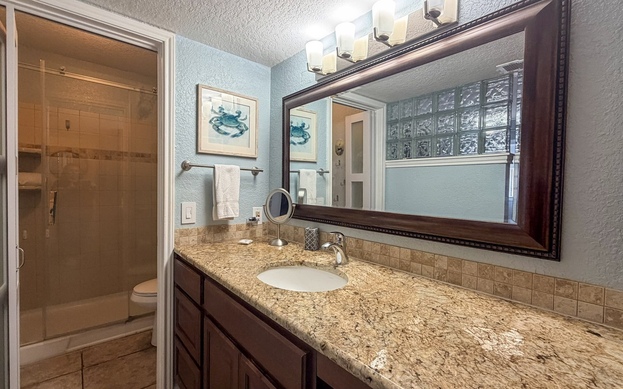 Your beautifully updated bathroom features granite countertops, coastal artwork, and a spacious shower for your comfort and convenience.