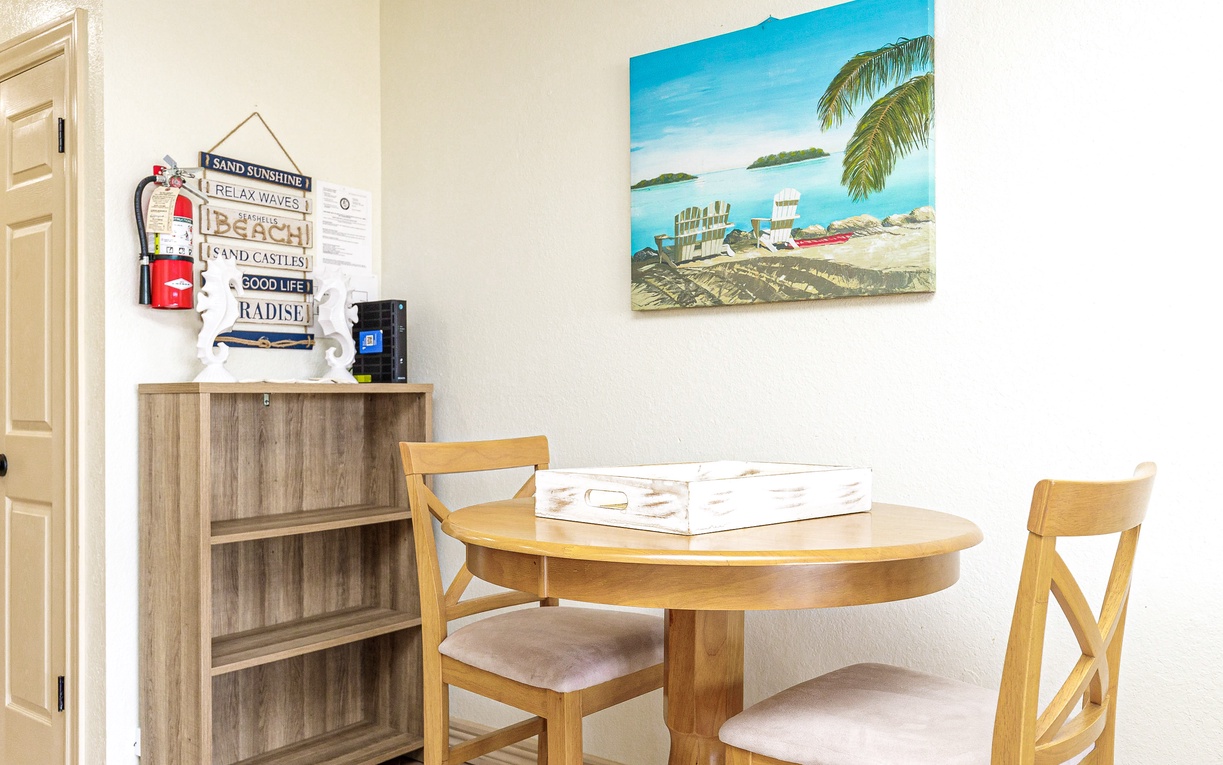 Enjoy morning coffee at your cozy dining nook, where tropical artwork and thoughtful touches create the perfect breakfast spot.