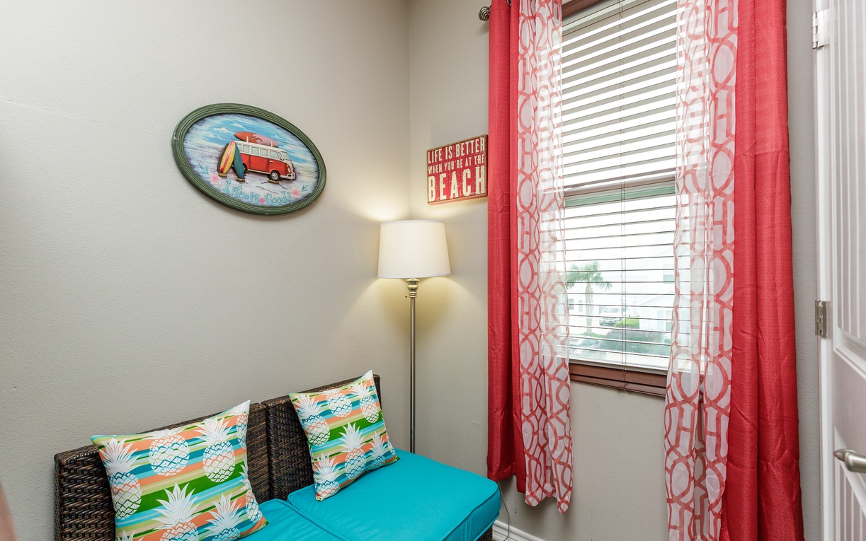 Relax in your cozy reading nook with cheerful beach-themed decor, tropical pillows, and warm natural light streaming through coral curtains.