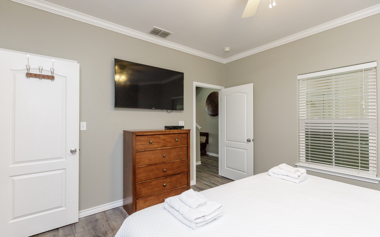 Your peaceful bedroom features a wall-mounted TV, convenient storage, and fresh towels waiting for your arrival.