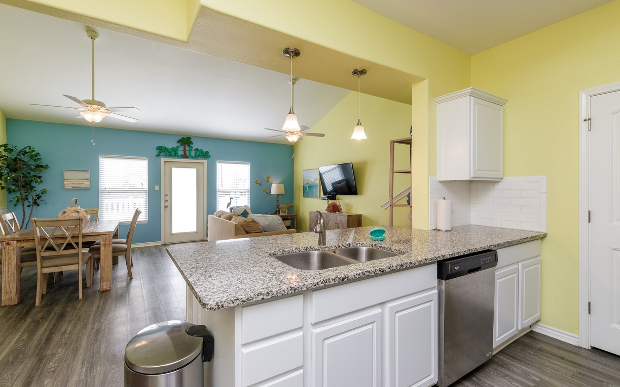 Your bright, open kitchen flows into a tropical-inspired living space where cheerful yellows meet coastal blues, creating the perfect backdrop for vacation memories.