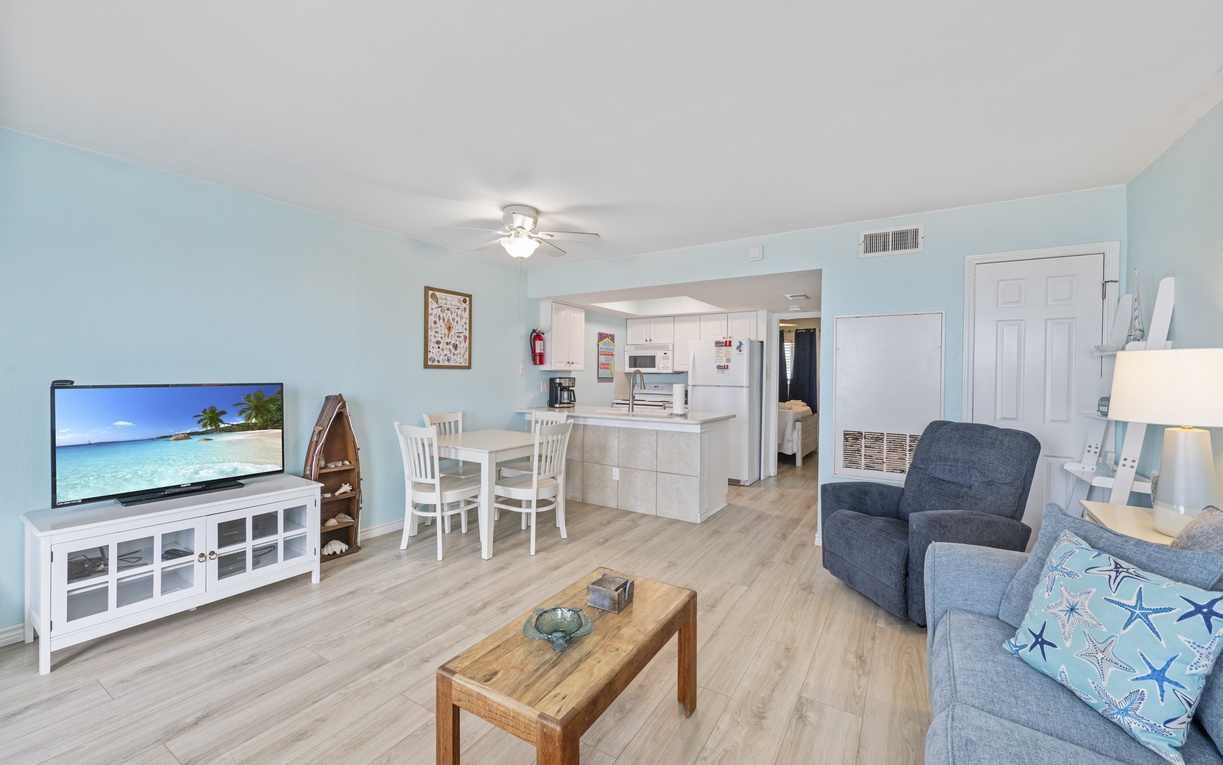 Relax in your bright open-concept space with modern kitchen, comfortable seating, and large TV for cozy evenings.