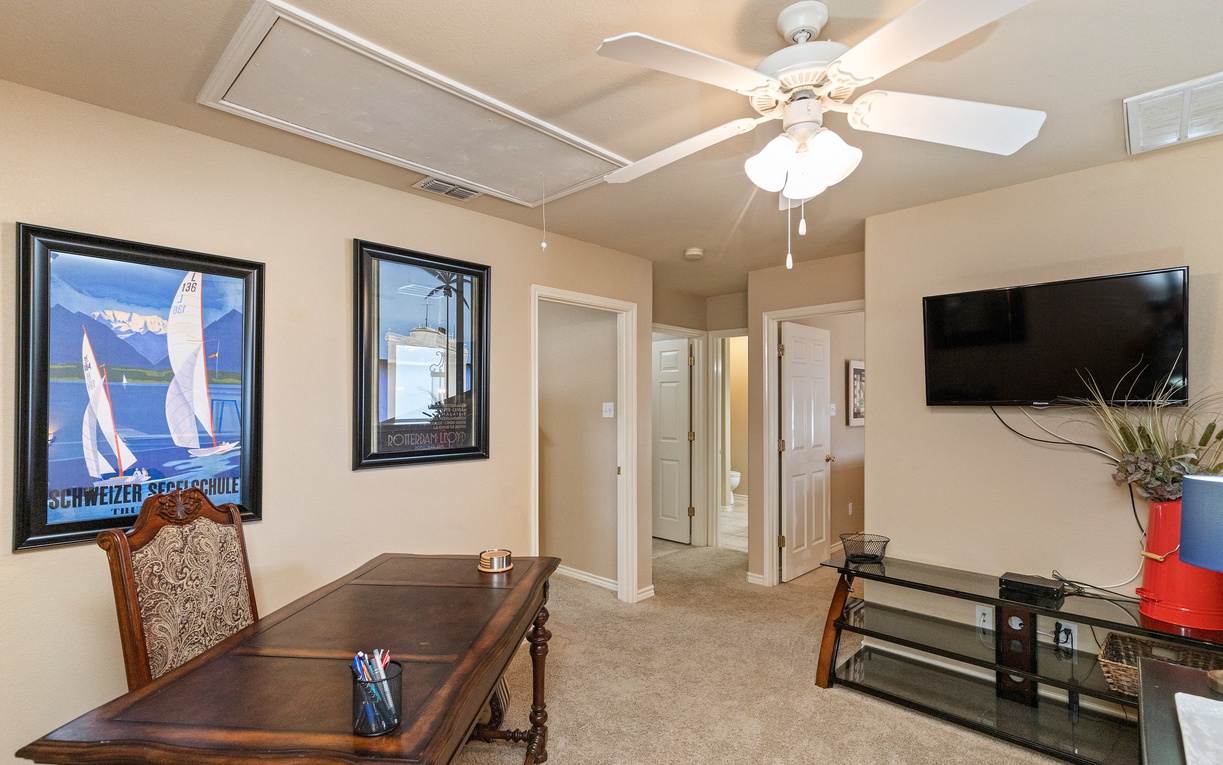 Your dedicated workspace awaits with a stately wooden desk and entertainment center, perfectly positioned for productive mornings or relaxing evenings.