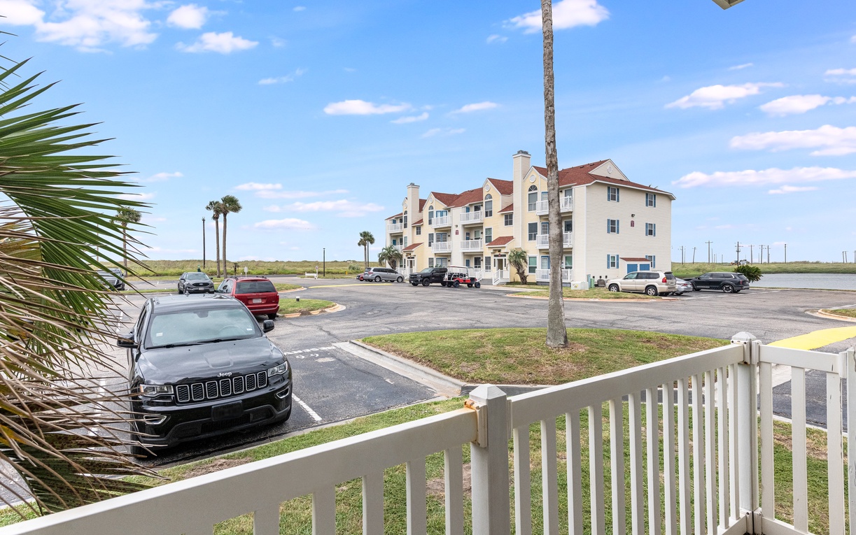 Beachside vacation rental complex with convenient parking and tropical palm trees under sunny skies.