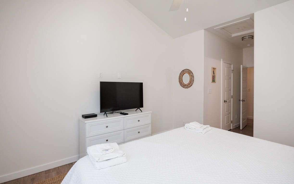 Relax in your peaceful bedroom with fresh linens, a flat-screen TV, and plenty of storage space in the white dresser.