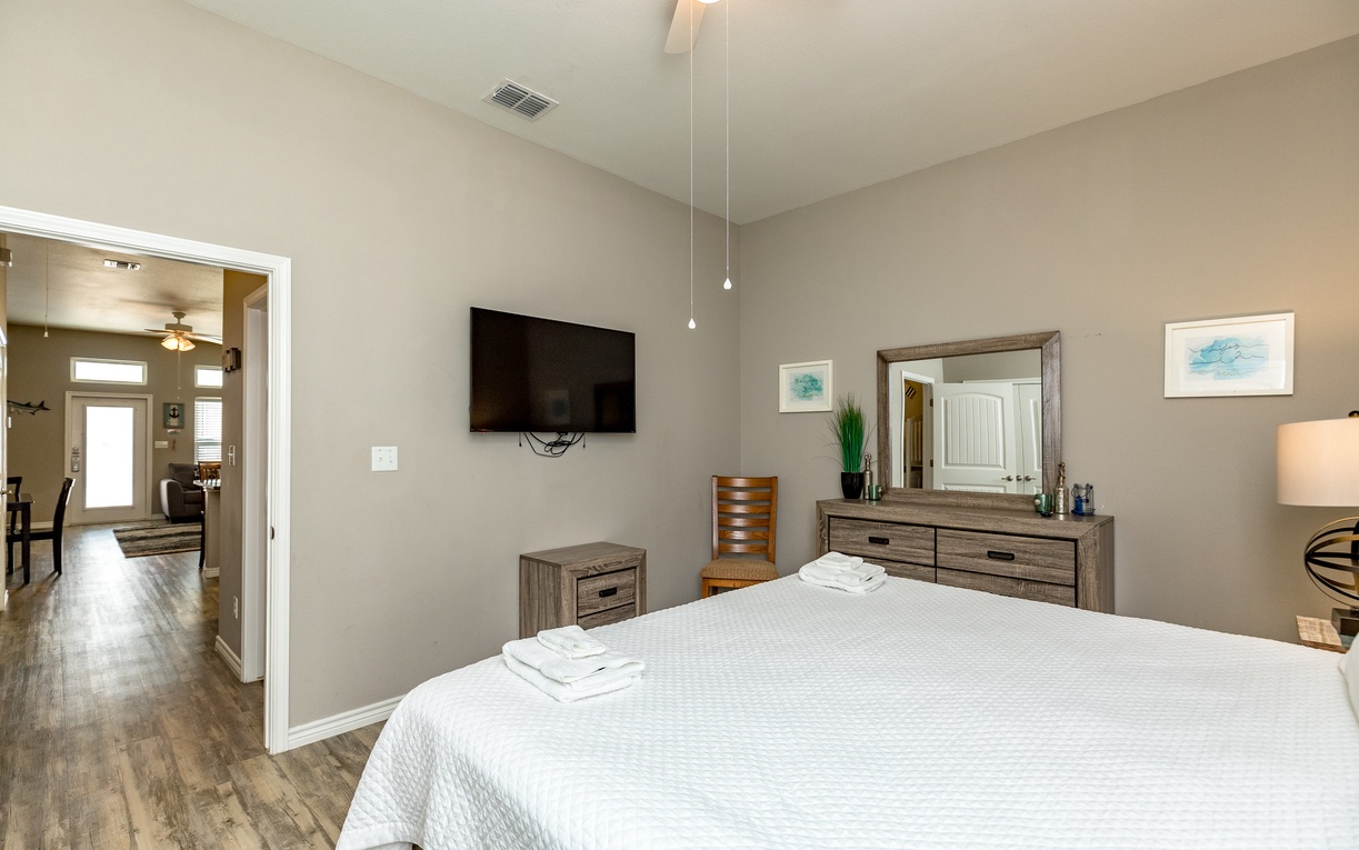 Unwind in your spacious bedroom with crisp linens, modern furnishings, and a wall-mounted TV for cozy evenings.