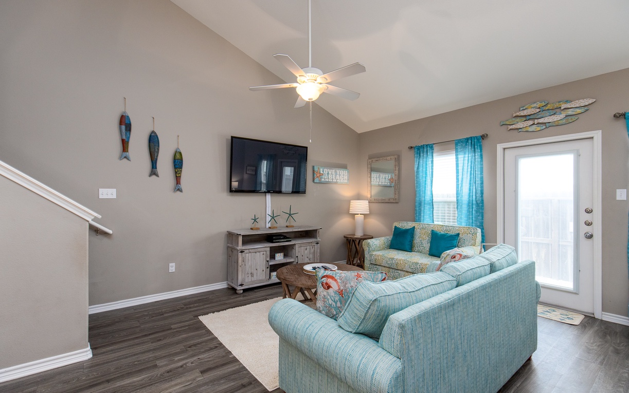 Relax in your coastal-inspired living room with plush seating, beach-themed décor, and modern amenities for perfect vacation comfort.