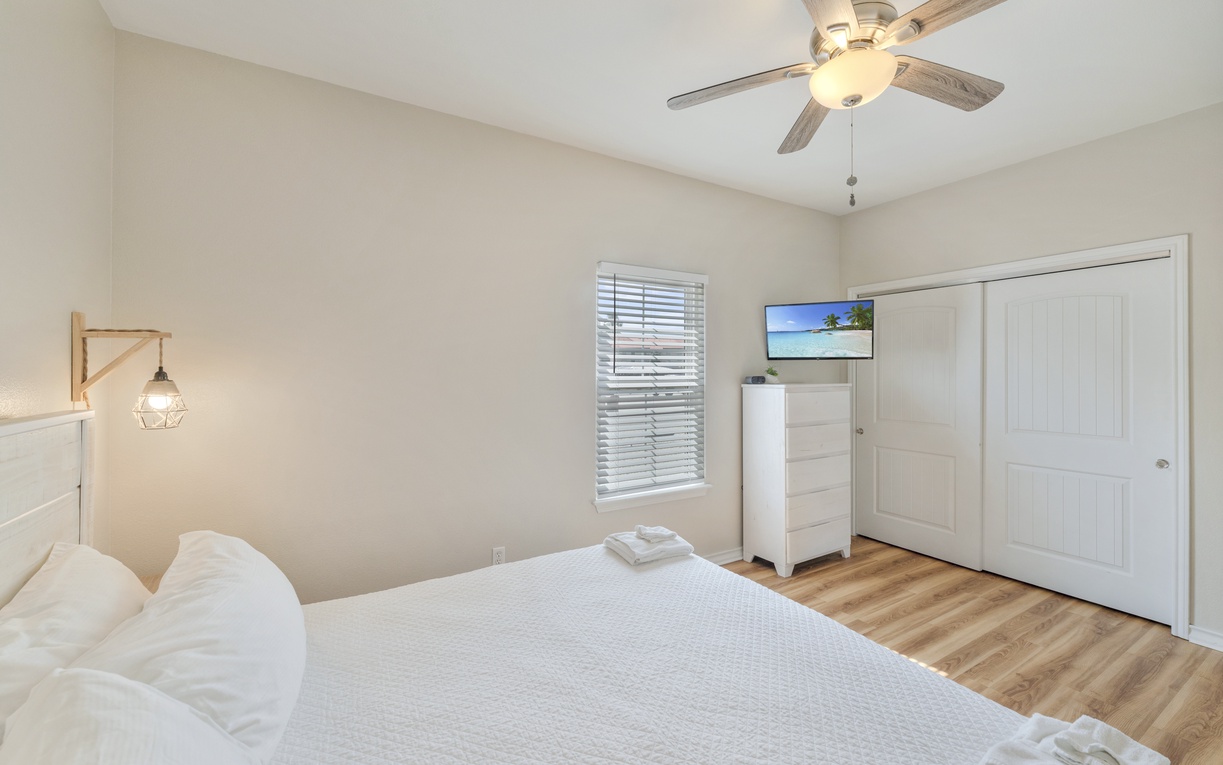Slip into crisp white linens and let the soft coastal breeze from your ceiling fan lull you to sleep. Your serene bedroom retreat awaits, with warm wood floors and charming touches throughout.