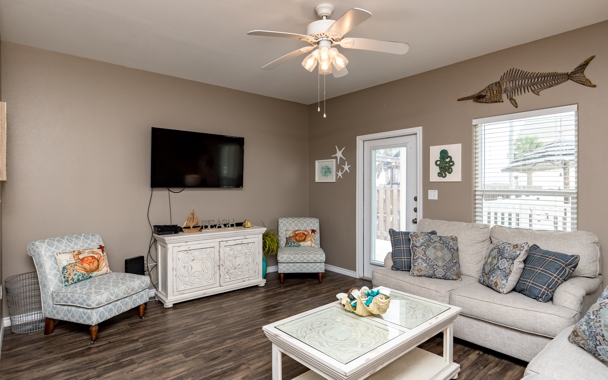 Relax in your coastal-themed living room with comfortable seating, large TV, and beach-inspired decor that creates the perfect atmosphere for unwinding.