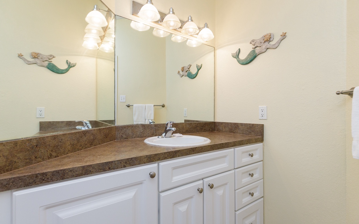 Refresh in your coastal-themed bathroom with granite counters, ample vanity storage, and charming mermaid décor creating a whimsical seaside escape.