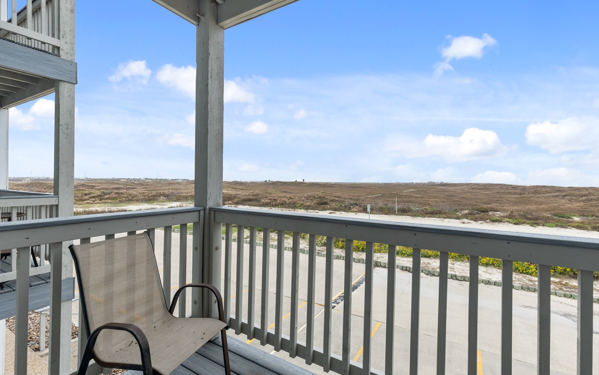 Step onto your private balcony and breathe in endless coastal views stretching across natural dunes under expansive blue skies.