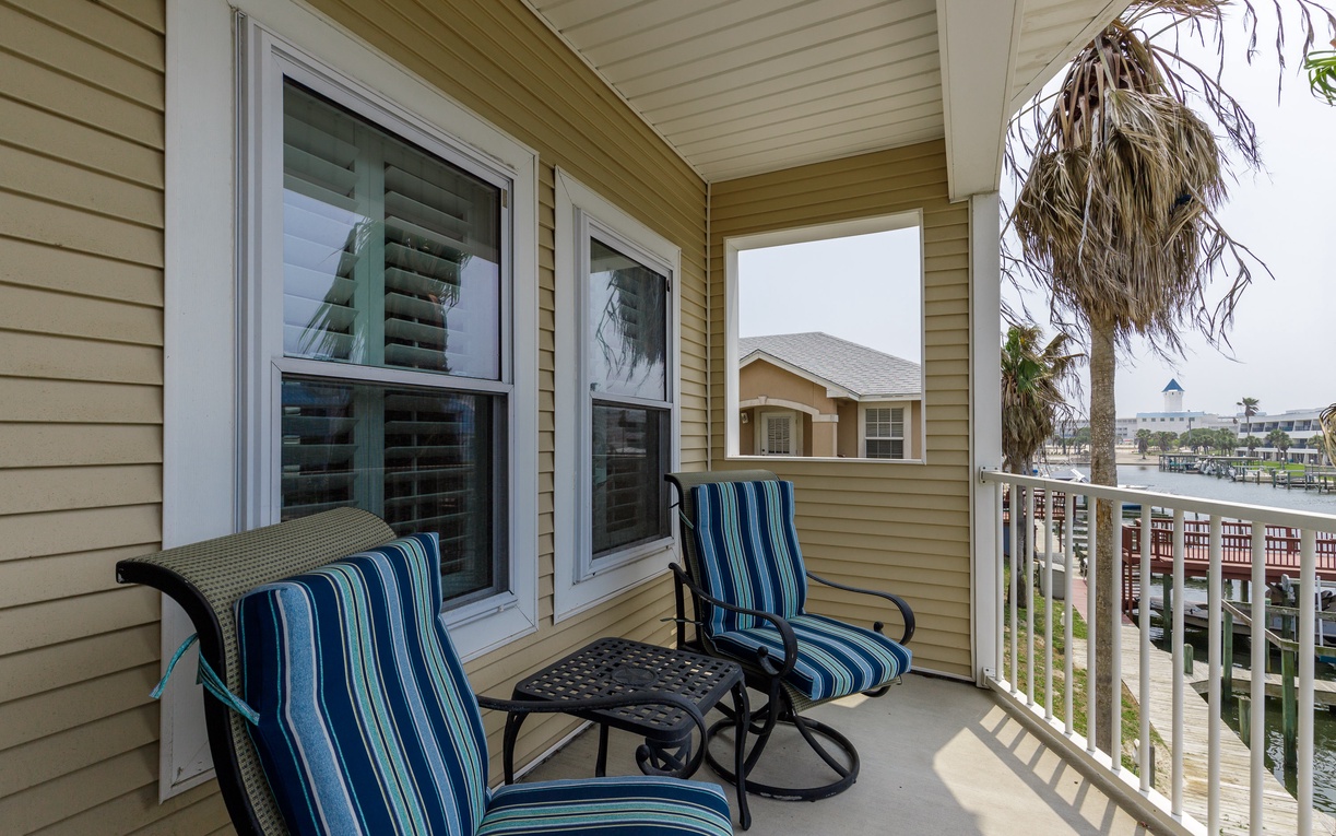 Unwind on your private balcony with comfortable striped chairs, perfect for morning coffee while watching boats drift by below.