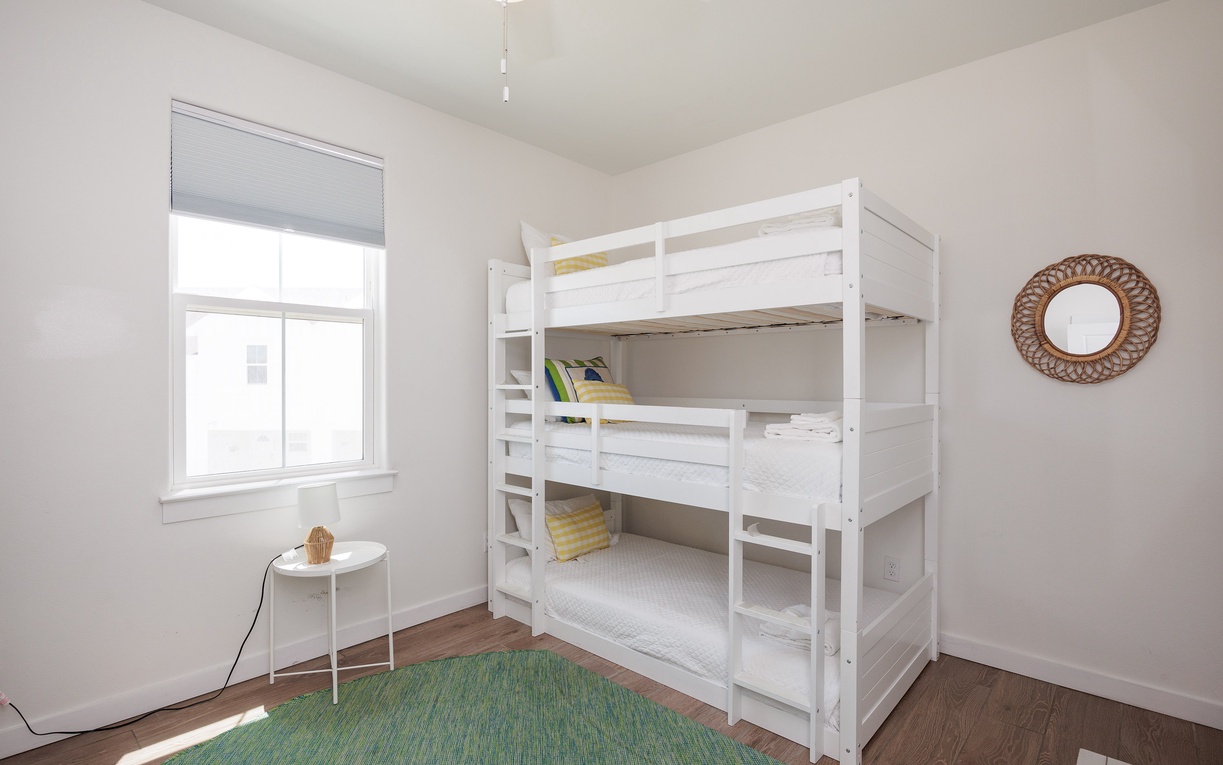 Your kids will love this cozy bunk room with natural light and space to play on the soft green rug.