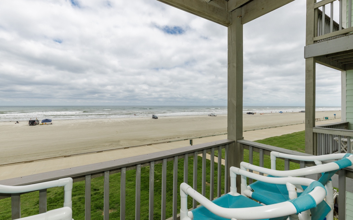 Unwind on your private balcony with turquoise chairs, watching waves roll onto the sandy shore below.