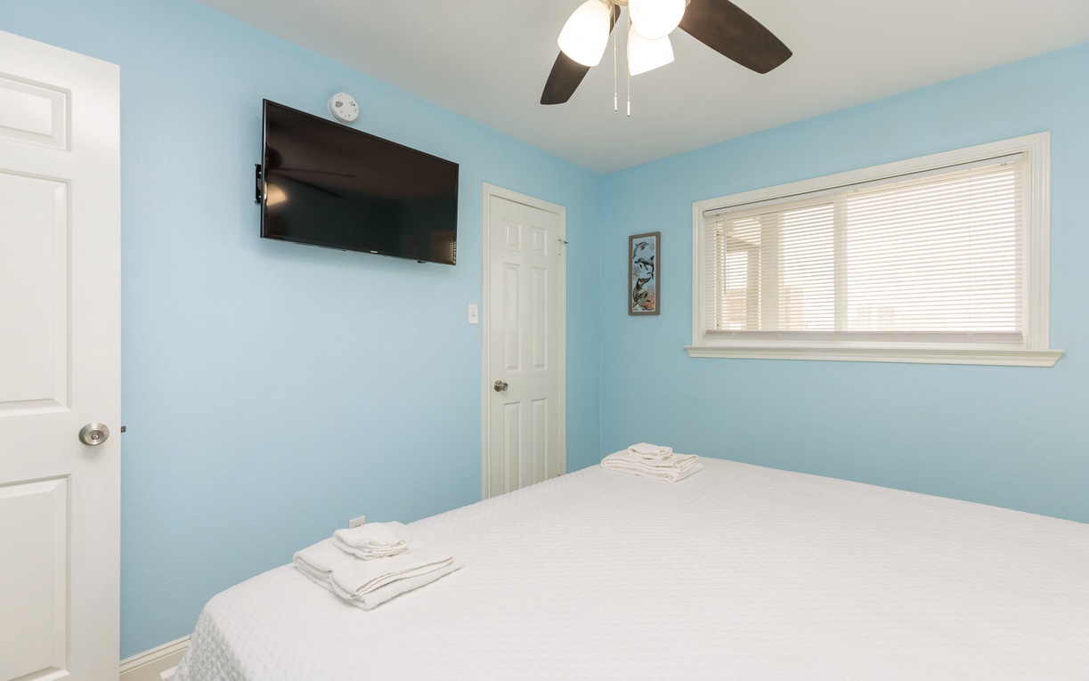 Drift off in your peaceful bedroom featuring soft blue walls, crisp linens, and modern amenities for ultimate relaxation.