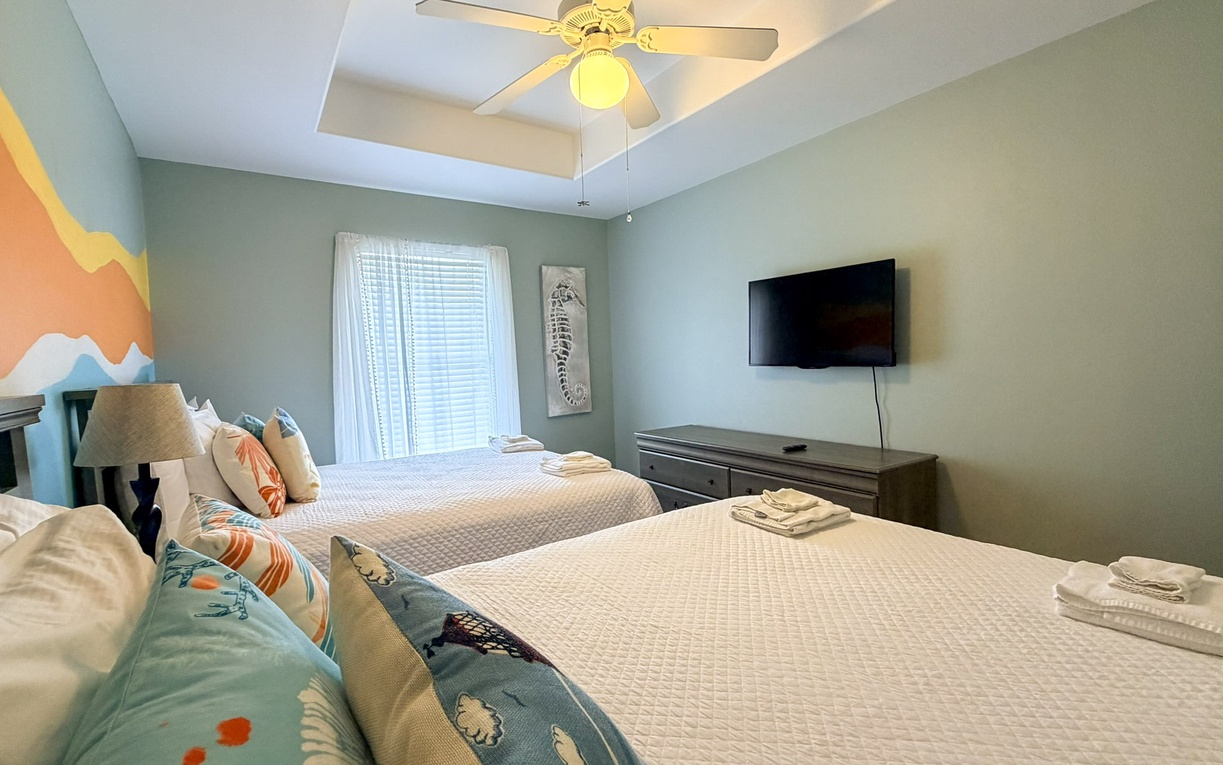Unwind in your peaceful bedroom featuring crisp white linens, a wall-mounted TV, and soothing sage walls that create the perfect retreat.